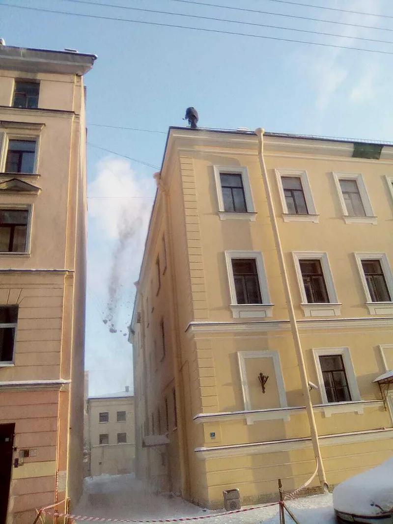 Сброс снега с крыши жилого дома в центре СПб, альпинист на кровле